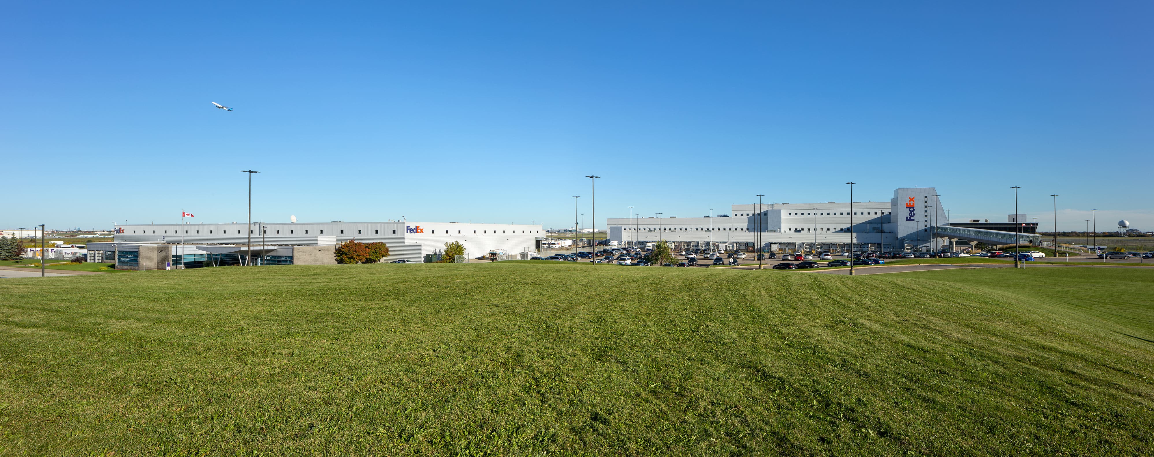 project-fedex-yyz-7-b a large grassy field with cars parked in the background